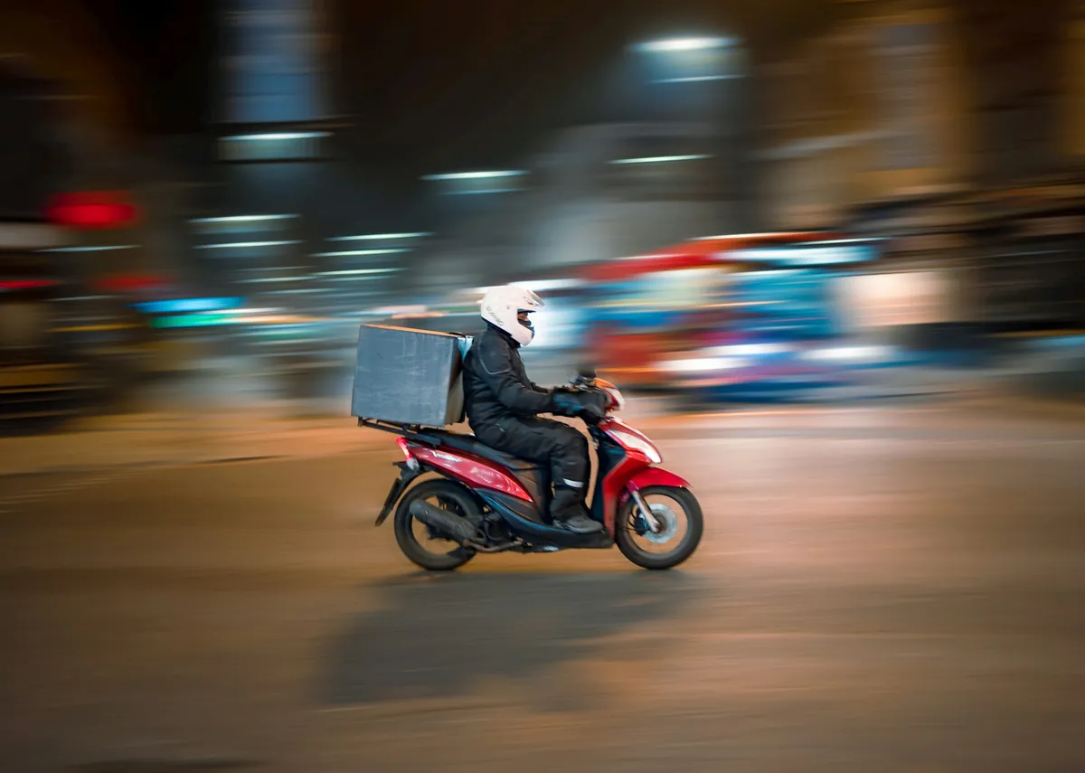 Repartidor en moto llevando un pedido de noche
