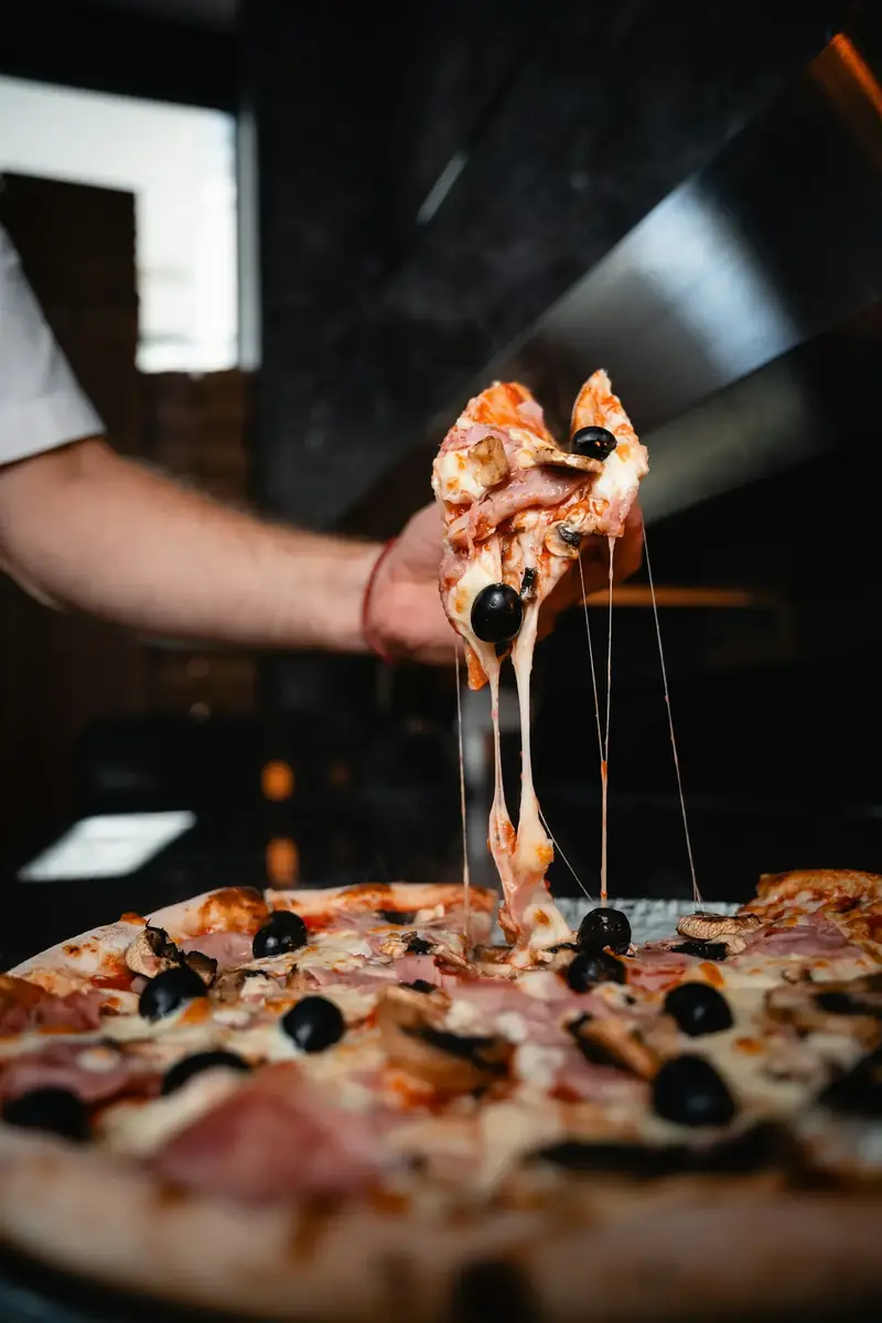 Porción de pizza levantada con hilos de queso