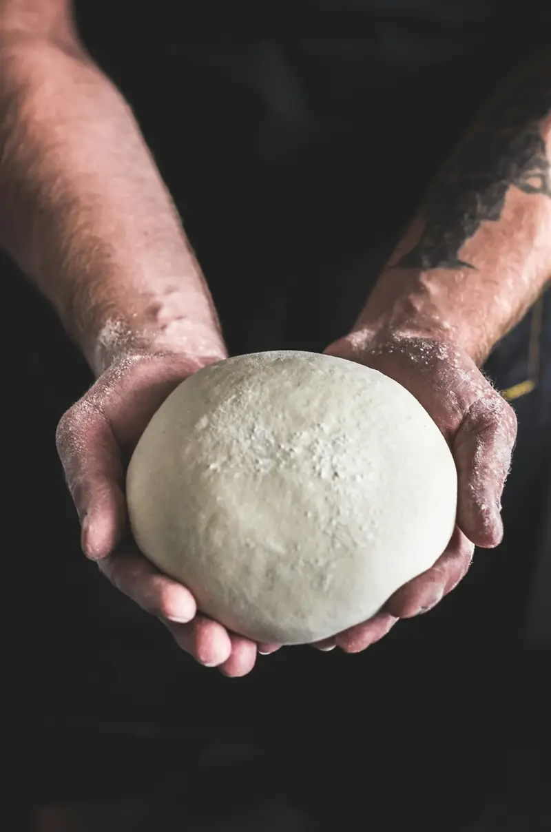 Pizzero sosteniendo una bola de masa artesanal