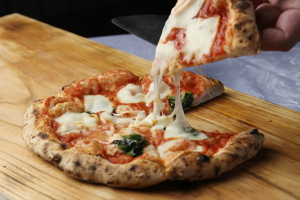Porción de pizza margarita con queso estirándose