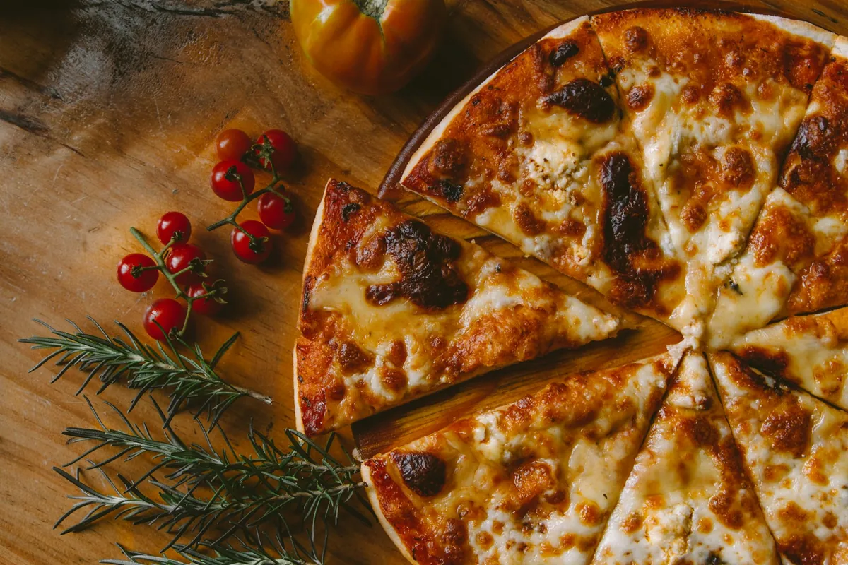Pizza de queso en rodajas sobre tabla de madera con tomates cherry